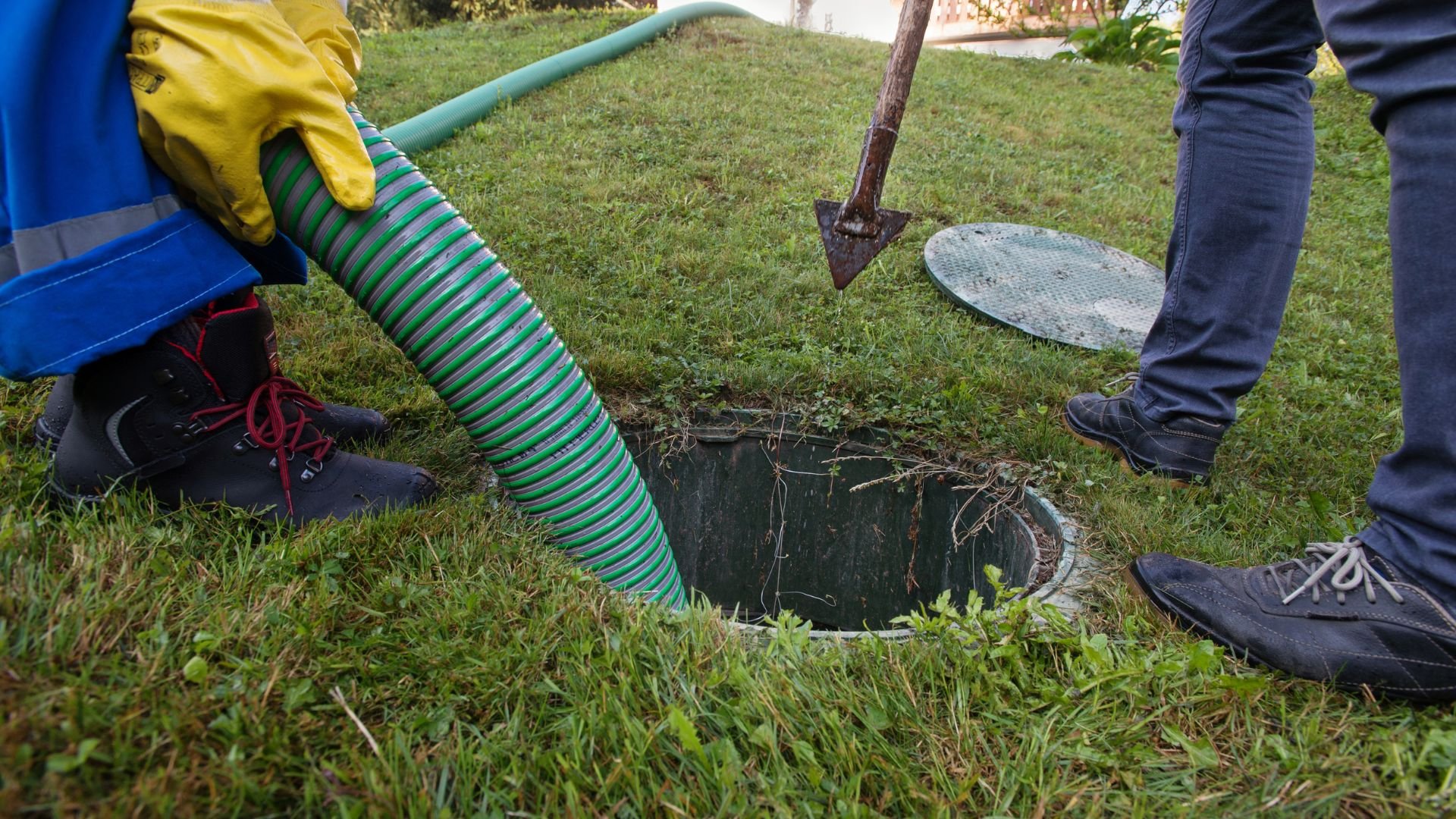 Workers using hose and shovel to inspect underground drainage system