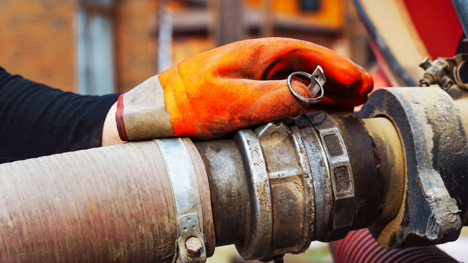 Orange gloved hand adjusting industrial machinery connection